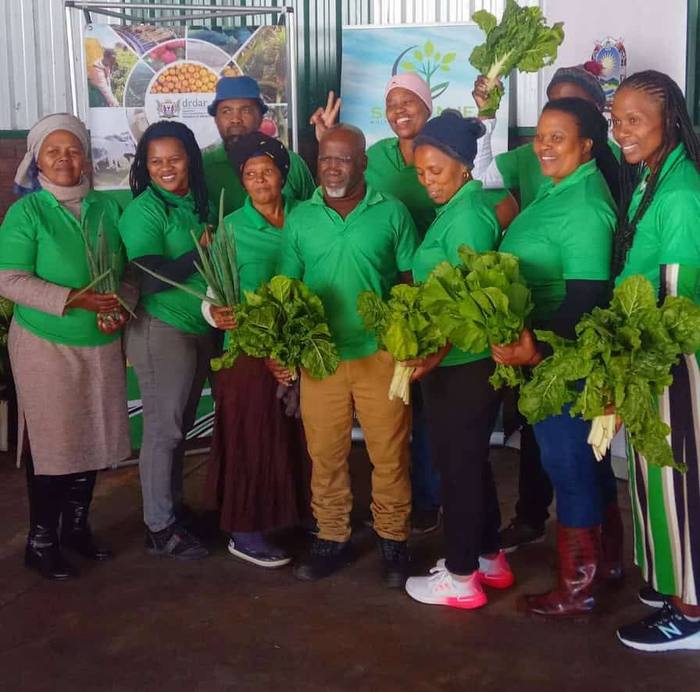 Isithembiso team holding freshly harvested vegetables