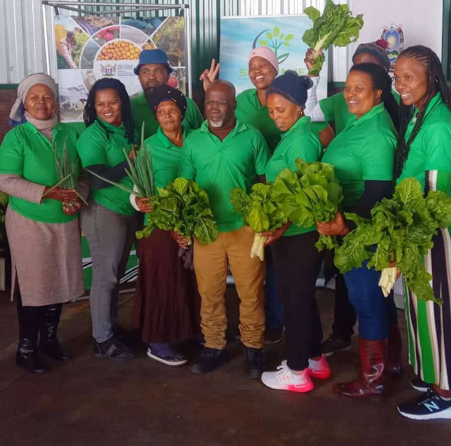 Isithembiso team members holding freshly harvested vegetables